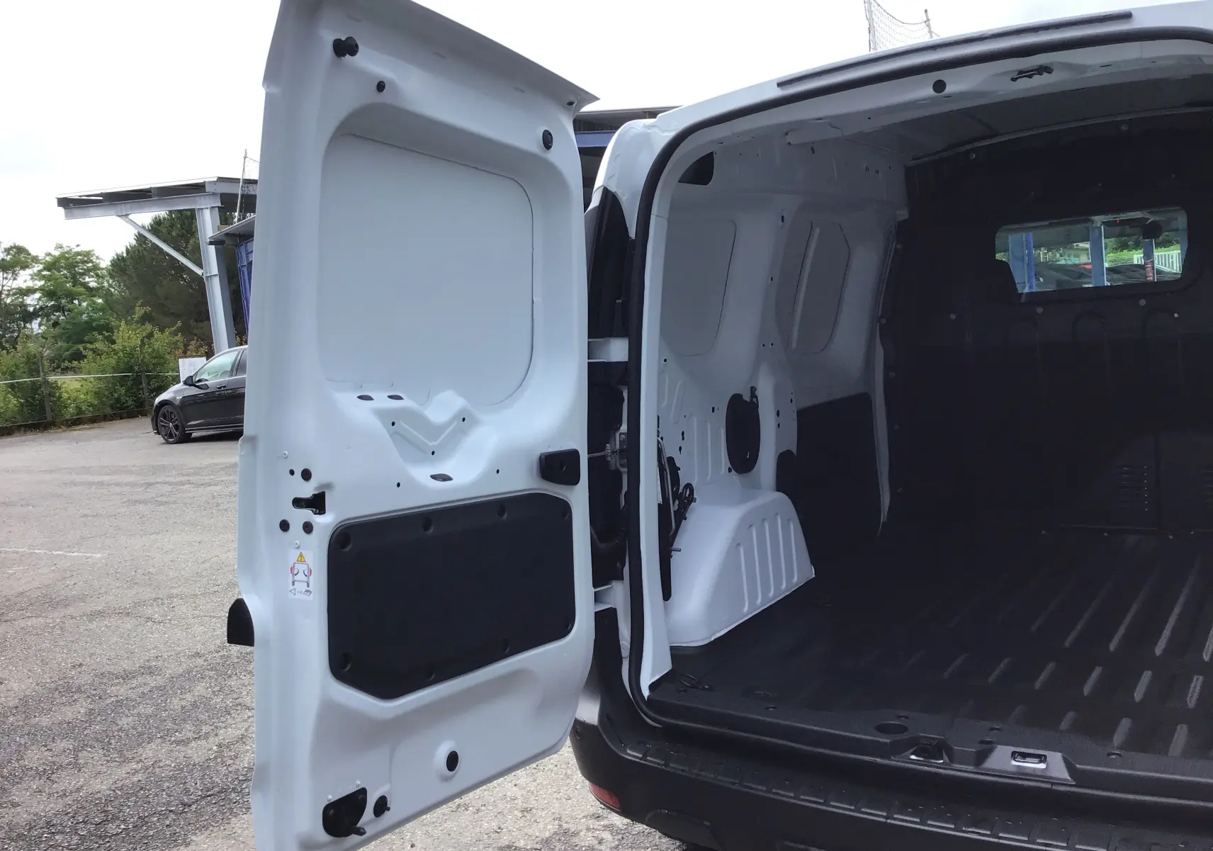 Vue arrière ouverte du Renault Express Van blanc 2024, montrant l'espace de chargement avec plancher en PVC et cloison séparatrice.