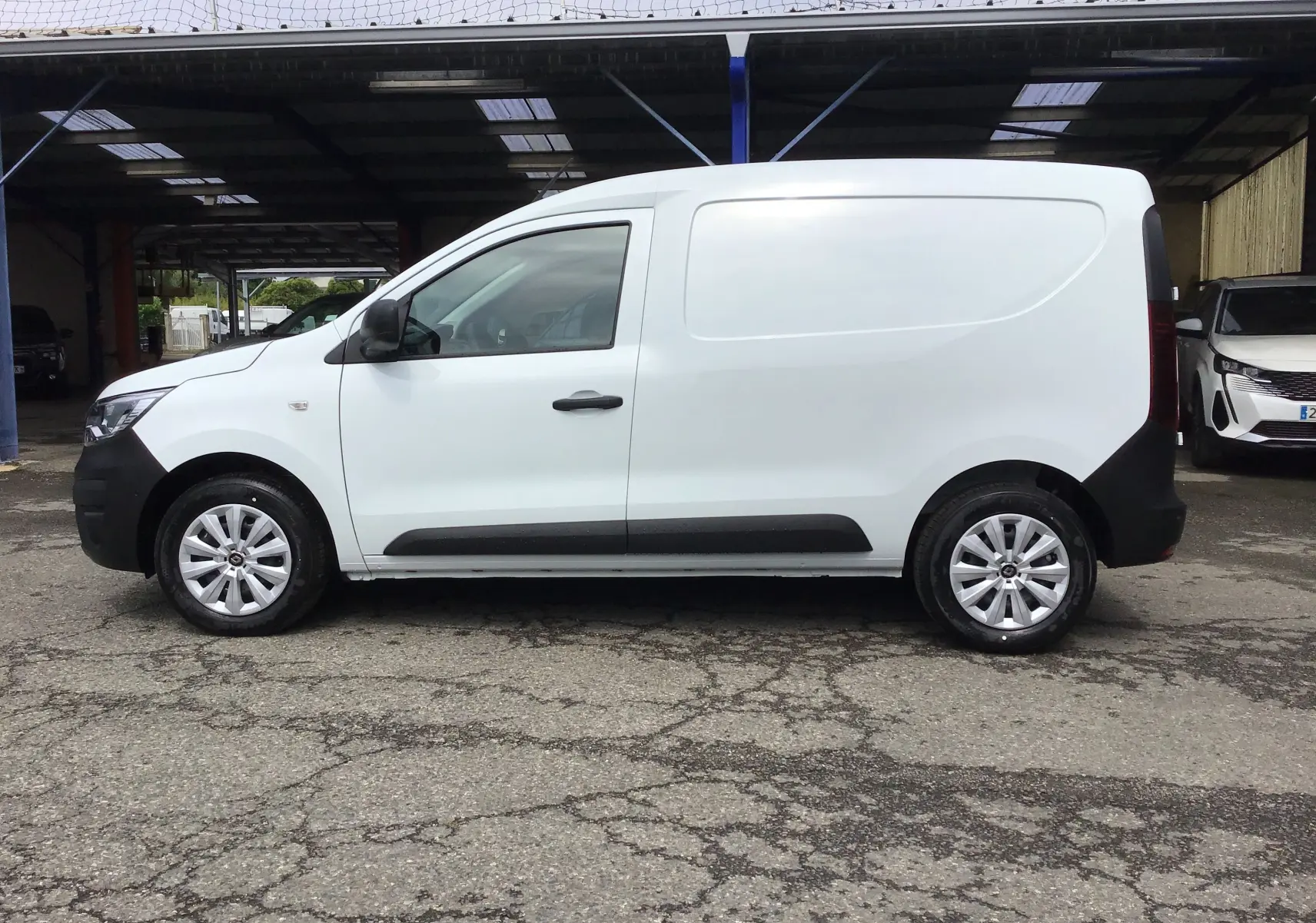 Profil droit d'un utilitaire Renault Express Van blanc 2024 avec protections noires et jantes argentées.