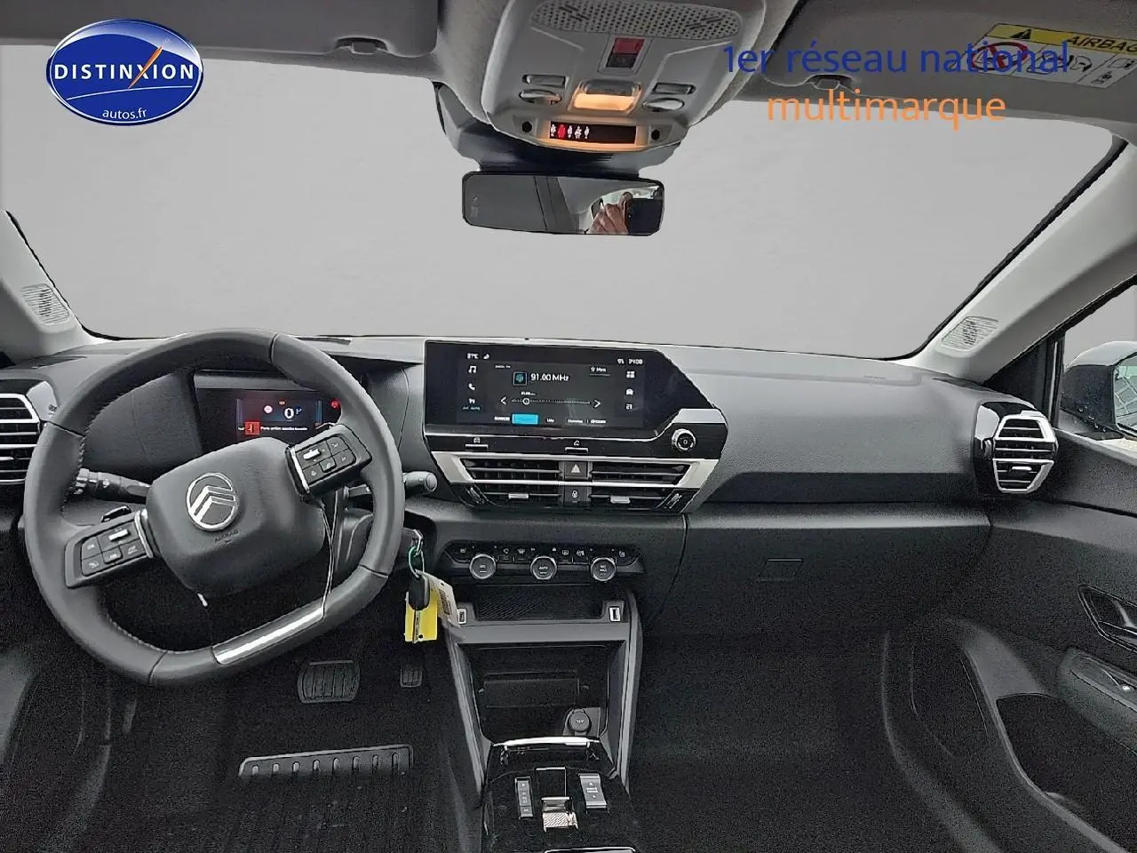 Vue avant intérieure du poste de conduite d'une Citroën C4 gris mercury, avec écran tactile central et volant cuir noir.