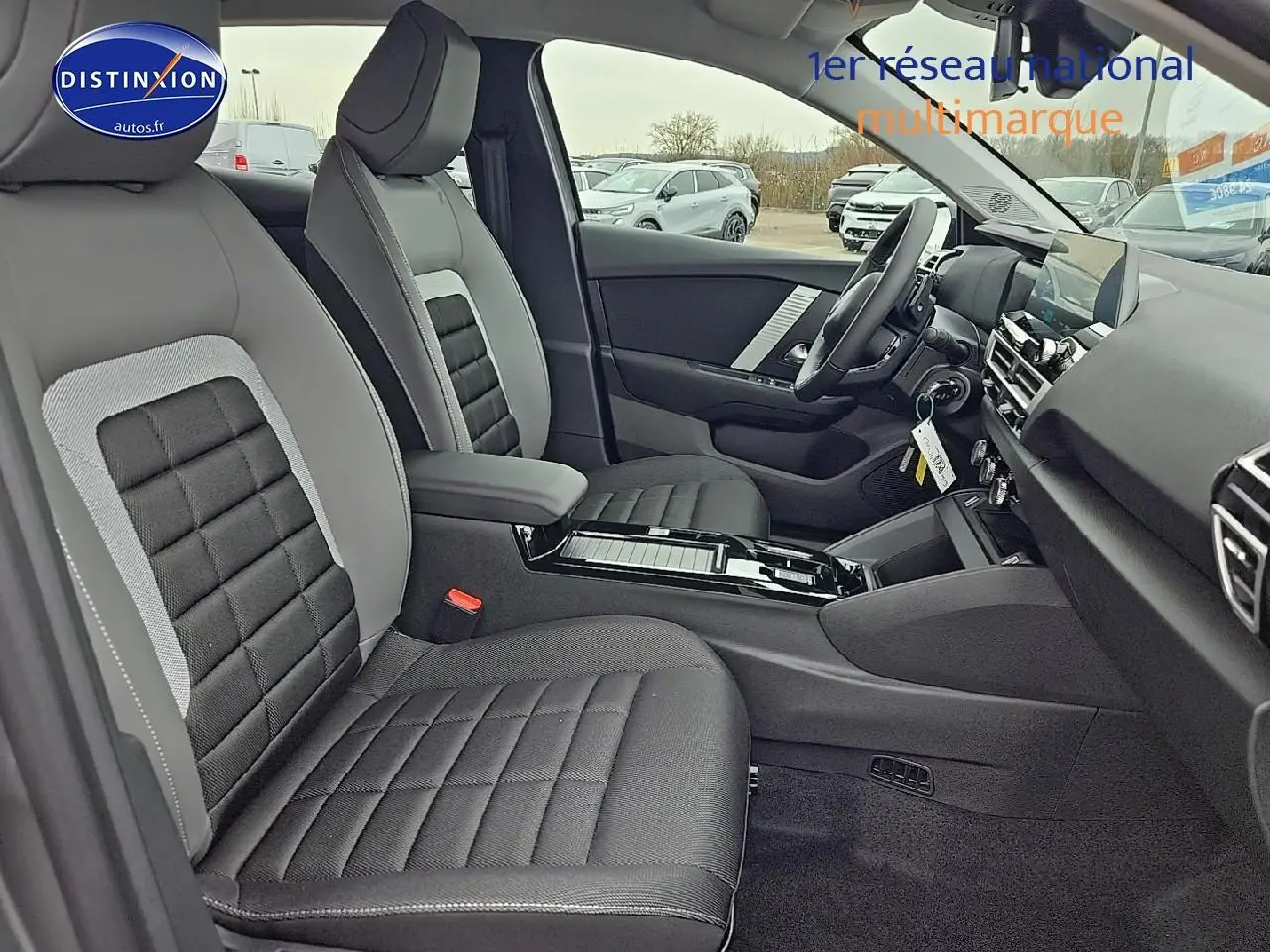 Intérieur avant droit de la Citroën C4 1.2 hybride 136 plus, sièges tissu noir et gris avec console centrale brillante.
