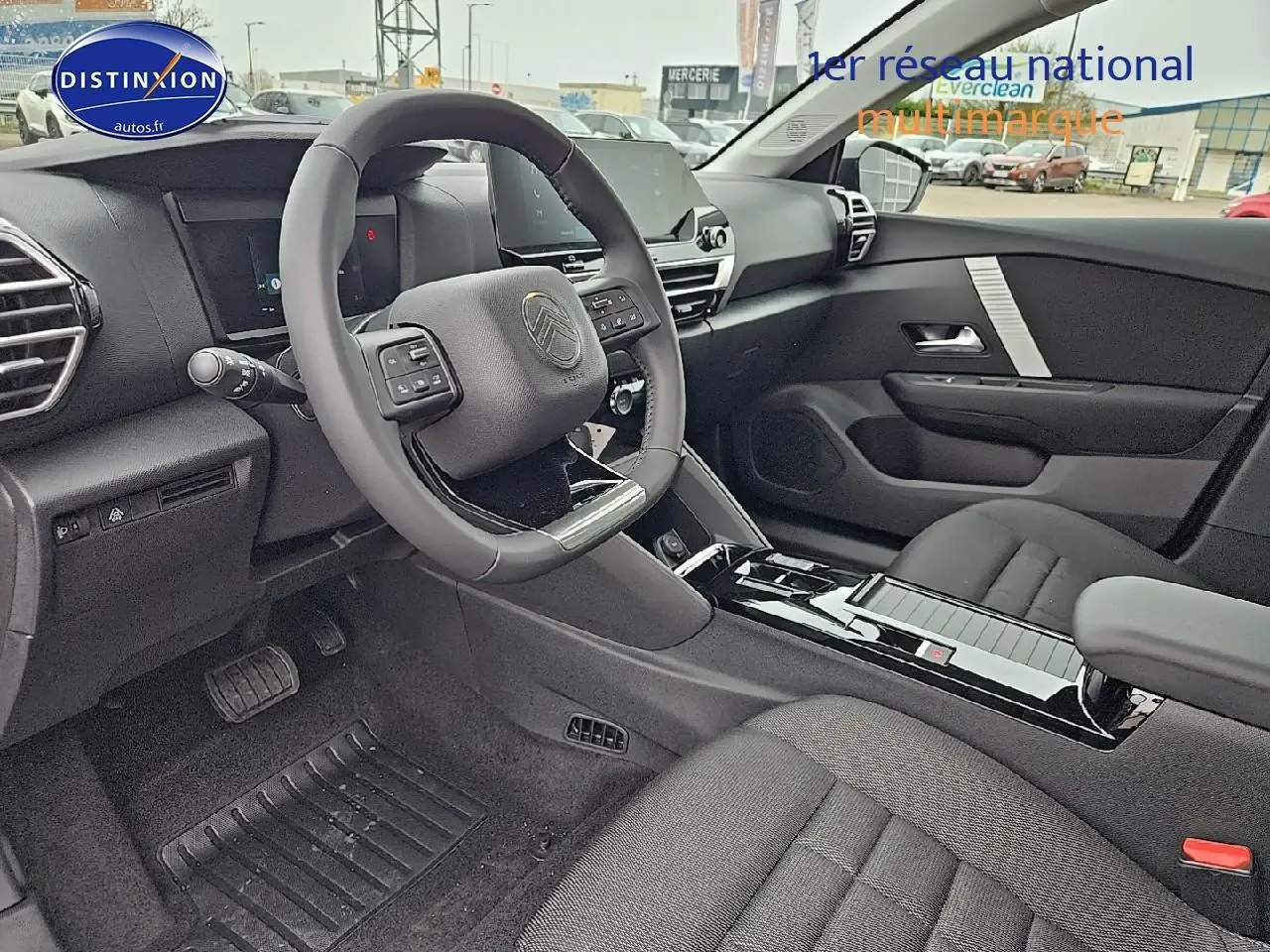 Intérieur avant droit d'une Citroën C4 gris mercury 2025 avec volant cuir et console centrale brillante noire