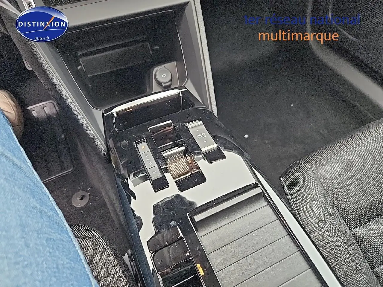 Gros plan sur la console centrale noire brillante de la Citroën C4 gris mercury, avec commandes de boîte auto et prise 12V visible.