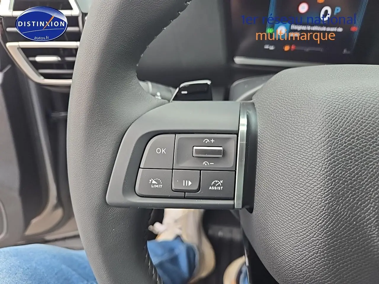 Gros plan sur les commandes gauche du volant cuir de la Citroën C4 gris mercury 2025 hybride.