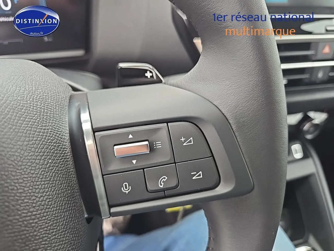 Gros plan sur les commandes au volant en cuir gris de la Citroën C4 1.2 hybride 136 plus, intérieur moderne et fonctionnel.