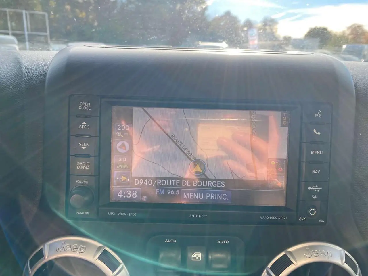 Écran de navigation central du Jeep Wrangler gris clair 2012, affichant une carte et les commandes environnantes.