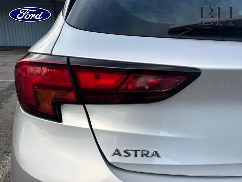 Gros plan sur le feu arrière gauche et le logo Astra d'une Opel Astra gris minéral, vue arrière côté gauche.