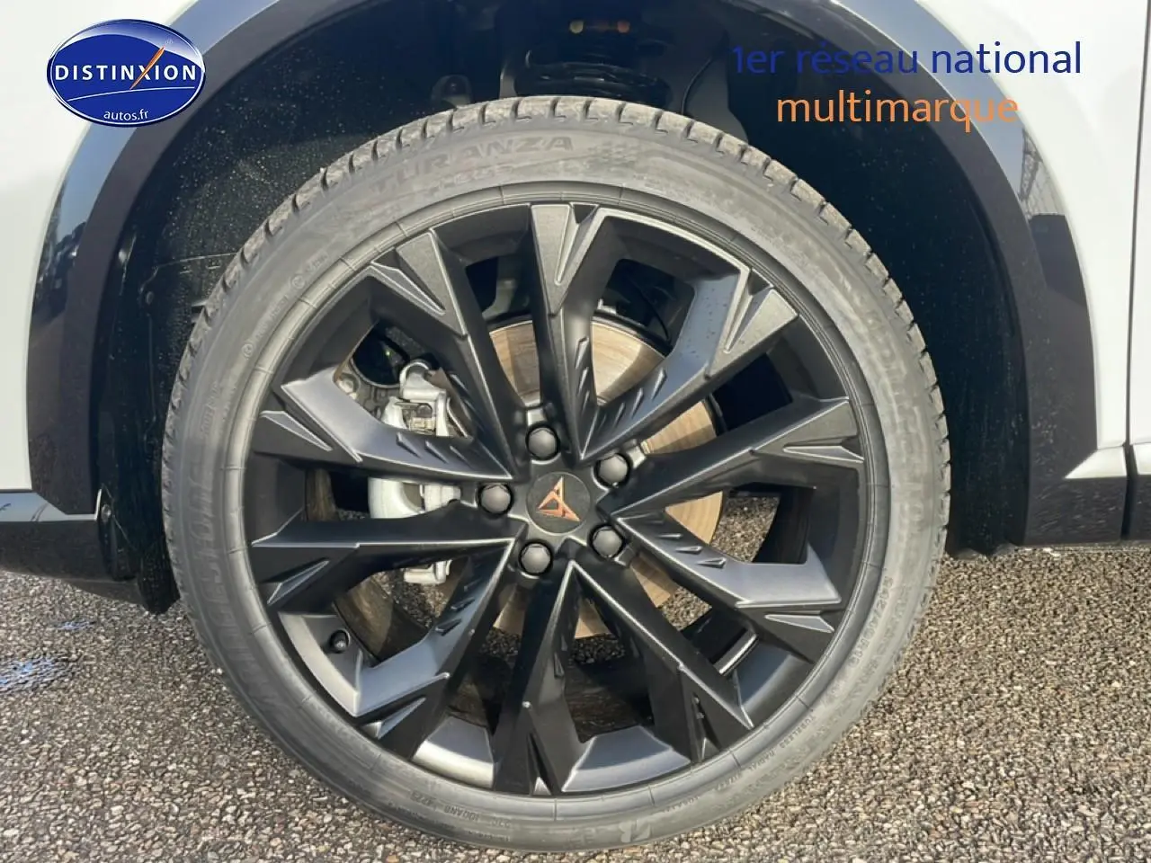 Gros plan sur la jante noire à design géométrique du côté avant droit d’un CUPRA Formentor blanc Nevada.