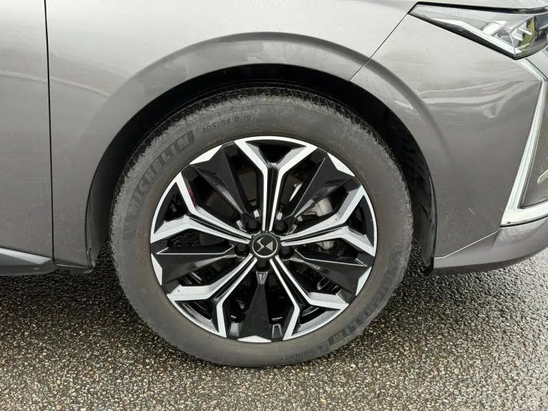 Gros plan sur la roue avant droite du DS4 2023 Gris Platinium, mettant en valeur la jante alliage noire et argentée au design complexe.