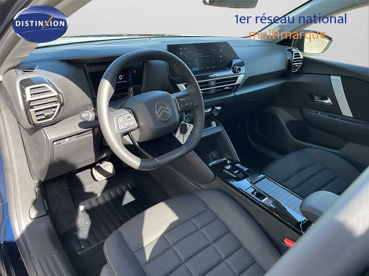 Vue intérieure côté conducteur de la Citroën C4 Hybrid 145ch avec tableau de bord moderne et sellerie tissu noir.