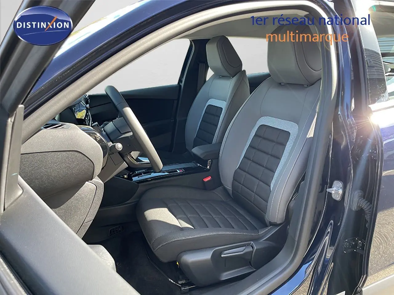 Vue intérieure côté conducteur d'une Citroën C4 bleu Eclipse Métal, mettant en valeur les sièges bi-matière gris et noir.