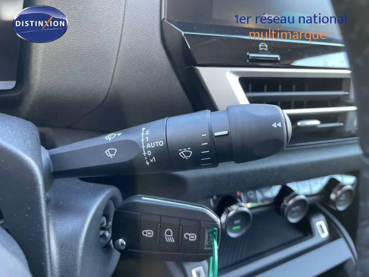 Gros plan sur la commande d’essuie-glace et la clé insérée dans le contacteur d’une Citroën C4 hybride, intérieur noir.