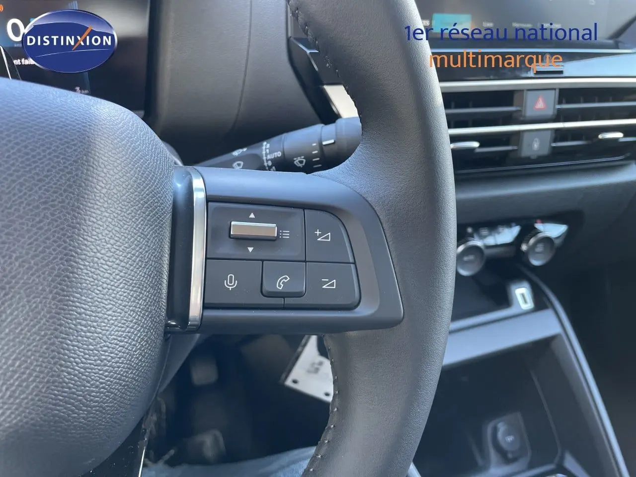 Gros plan sur les commandes au volant à gauche d'une Citroën C4 Hybrid 2026, intérieur noir avec tableau de bord moderne.