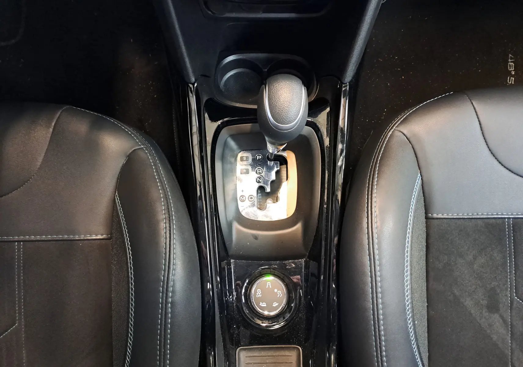 Vue plongeante sur la console centrale noire d'un Peugeot 2008 2019, montrant le levier de vitesse automatique et les sièges en cuir noir.