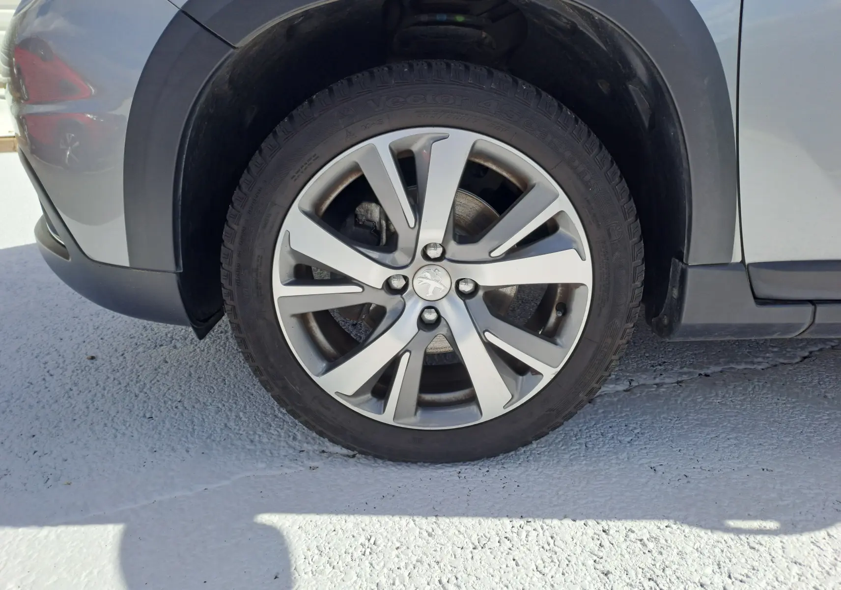 Gros plan sur la roue avant gauche grise d'un Peugeot 2008 2019 avec jante alliage à cinq branches doubles.