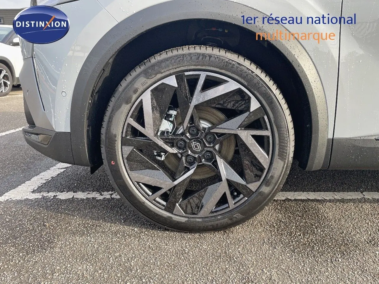 Gros plan sur la roue avant gauche du Renault Symbioz gris Rafale, mettant en valeur la jante noire et argentée au design géométrique.