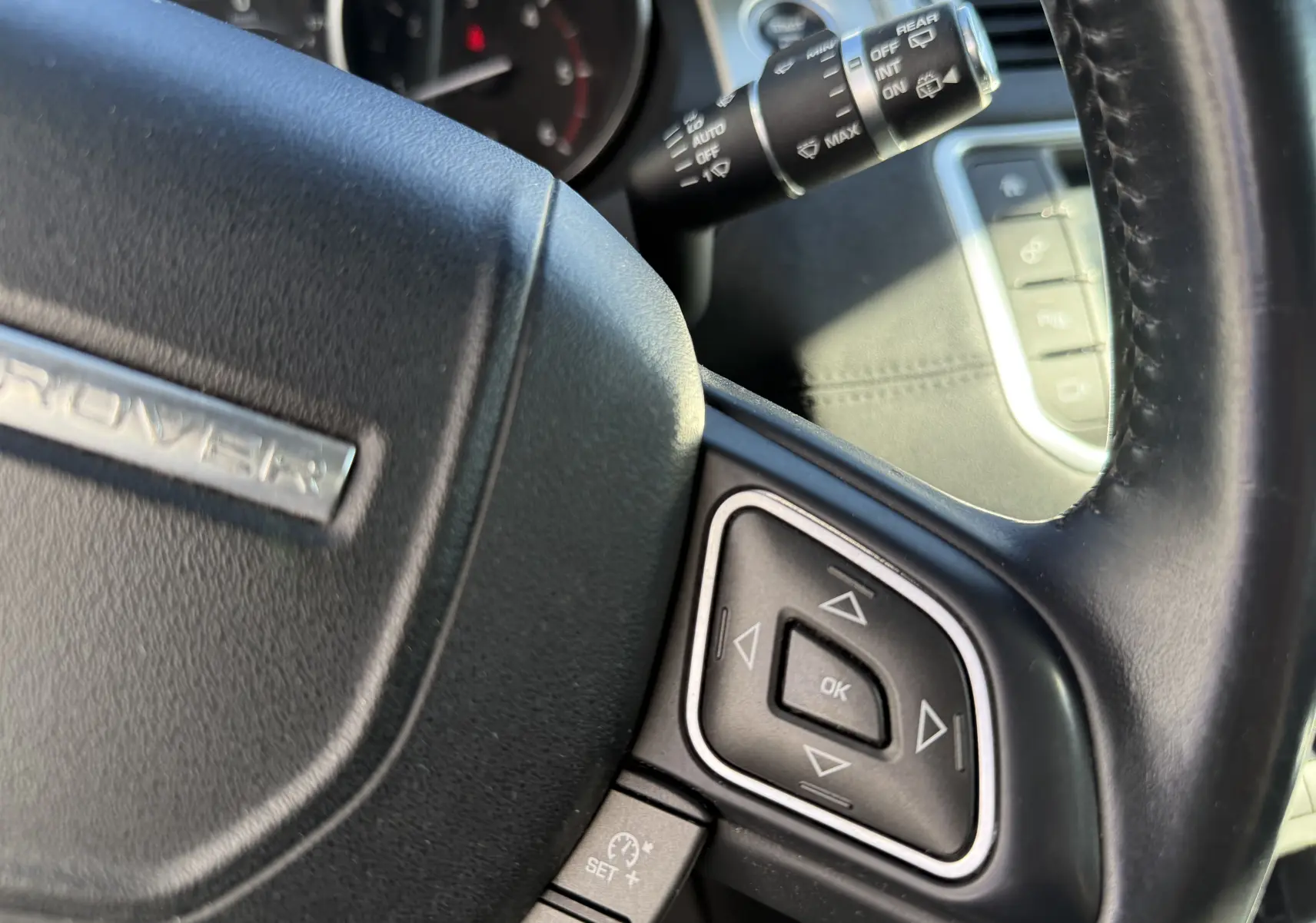 Gros plan sur le volant noir du Range Rover Evoque 2017, avec commandes multifonctions et levier d'essuie-glace visible.