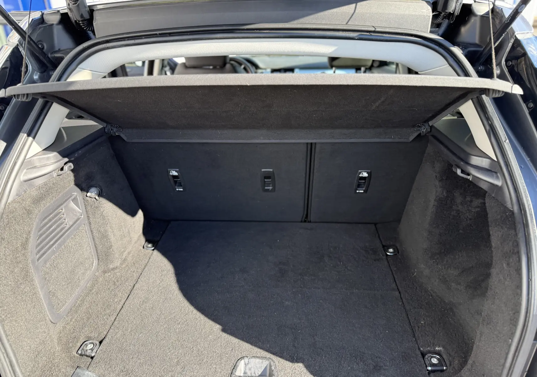 Vue intérieure du coffre ouvert d'un Range Rover Evoque gris, montrant un espace de rangement propre et bien fini.