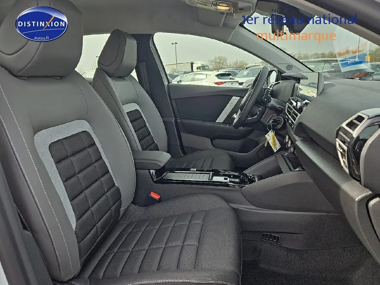 Intérieur de la Citroën C4 hybride 2025 vu côté droit, sièges tissu noir et gris avec console centrale moderne.