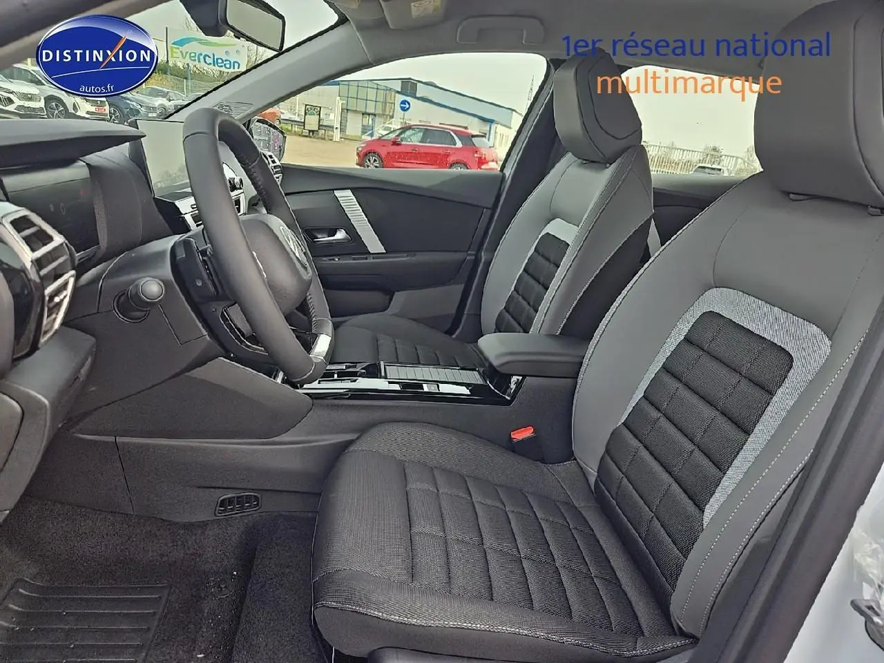 Intérieur avant droit de la Citroën C4 1.2 hybride blanc okenite avec sièges tissu noir et gris et volant cuir.