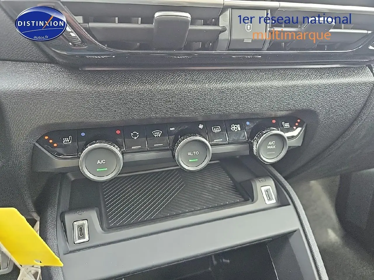Gros plan sur la console centrale de la Citroën C4 blanche, montrant les commandes de climatisation et deux prises USB.