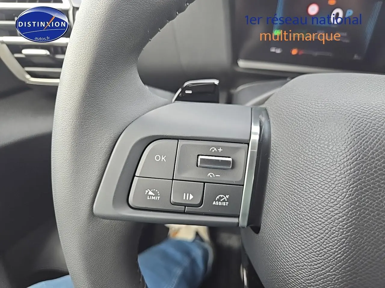 Gros plan sur les commandes au volant gauche du Citroën C4 blanc okenite, avec palettes de changement de vitesse visibles.