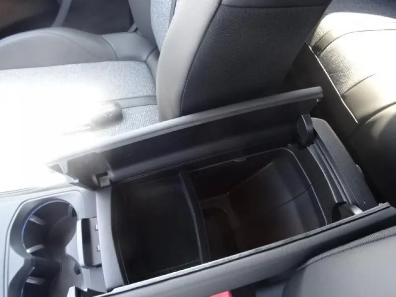 Coffre de console central ouvert montrant le rangement intérieur du Peugeot 3008 gris clair, vue de dessus côté conducteur.