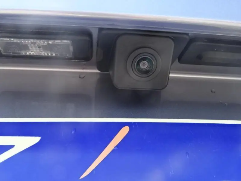 Gros plan sur la caméra de recul arrière du Peugeot 3008 gris clair, intégrée au-dessus de la plaque d'immatriculation.