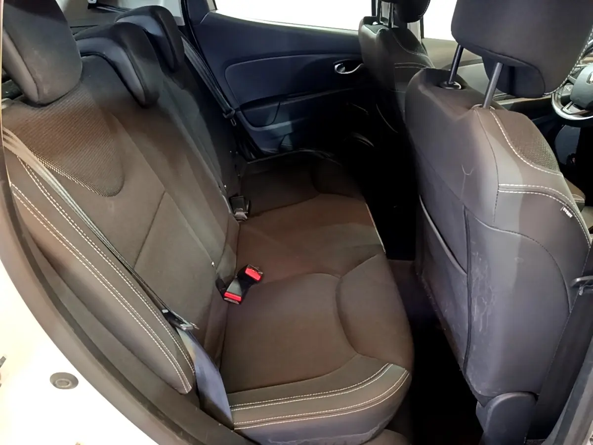 Vue intérieure côté gauche montrant la banquette arrière noire avec surpiqûres blanches d'une Renault Clio blanche 2016.