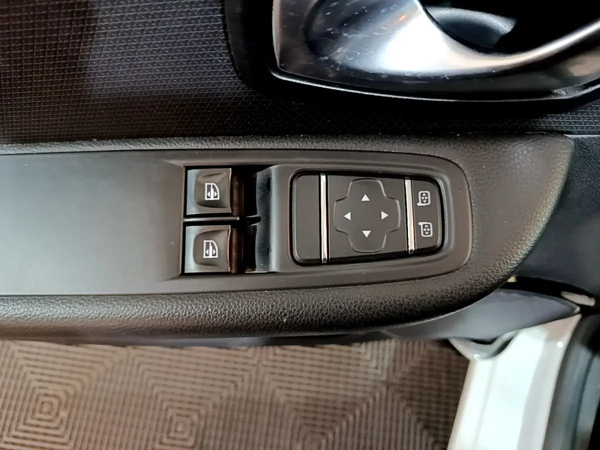 Gros plan sur les commandes de lève-vitres et réglage des rétroviseurs côté conducteur d’une Renault Clio blanche 2016.