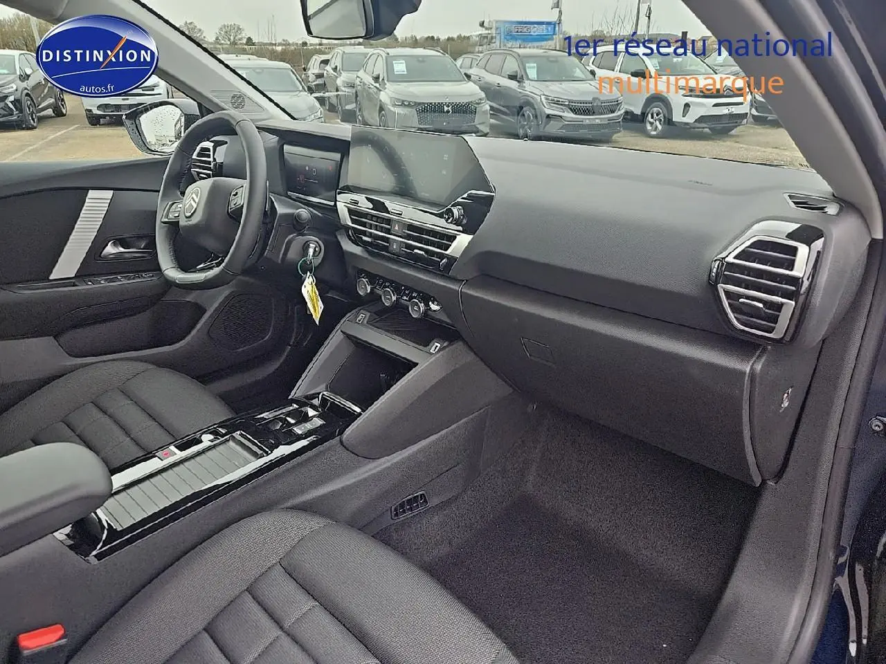 Intérieur avant droit de la Citroën C4 1.2 hybride 136 plus bleu eclipse avec tableau de bord moderne et sièges tissu noir.
