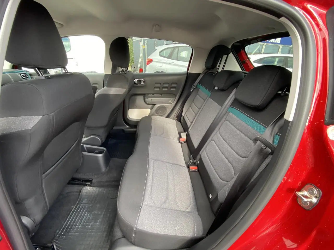 Vue intérieure côté droit de la banquette arrière grise avec ceinture et porte rouge vif d'une Citroën C3 Shine 2021.