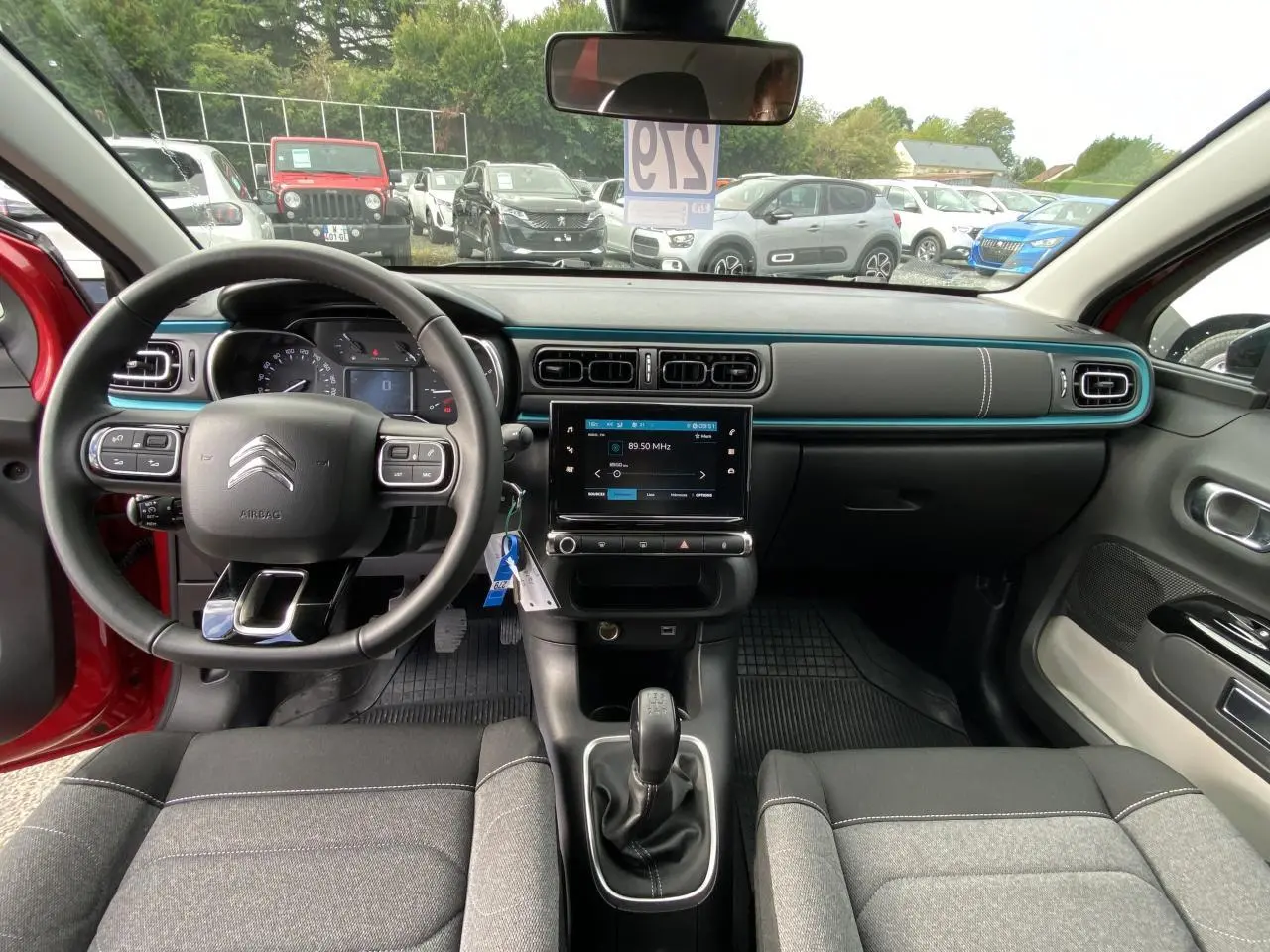 Vue intérieure avant de la Citroën C3 2021 rouge, volant multifonction et tableau de bord avec écran tactile central.