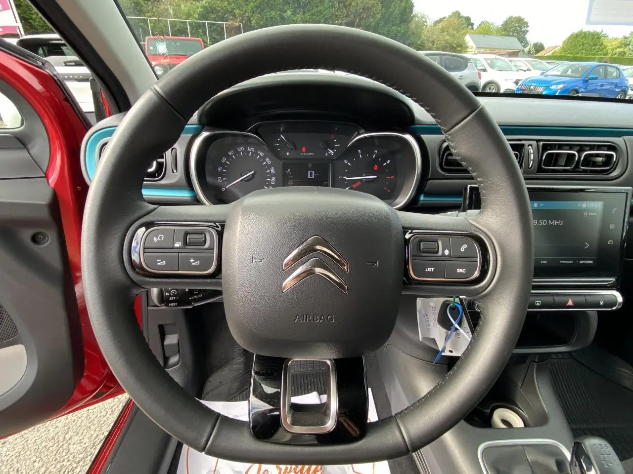 Vue rapprochée du volant noir de la Citroën C3 2021 avec tableau de bord et écran tactile en arrière-plan.