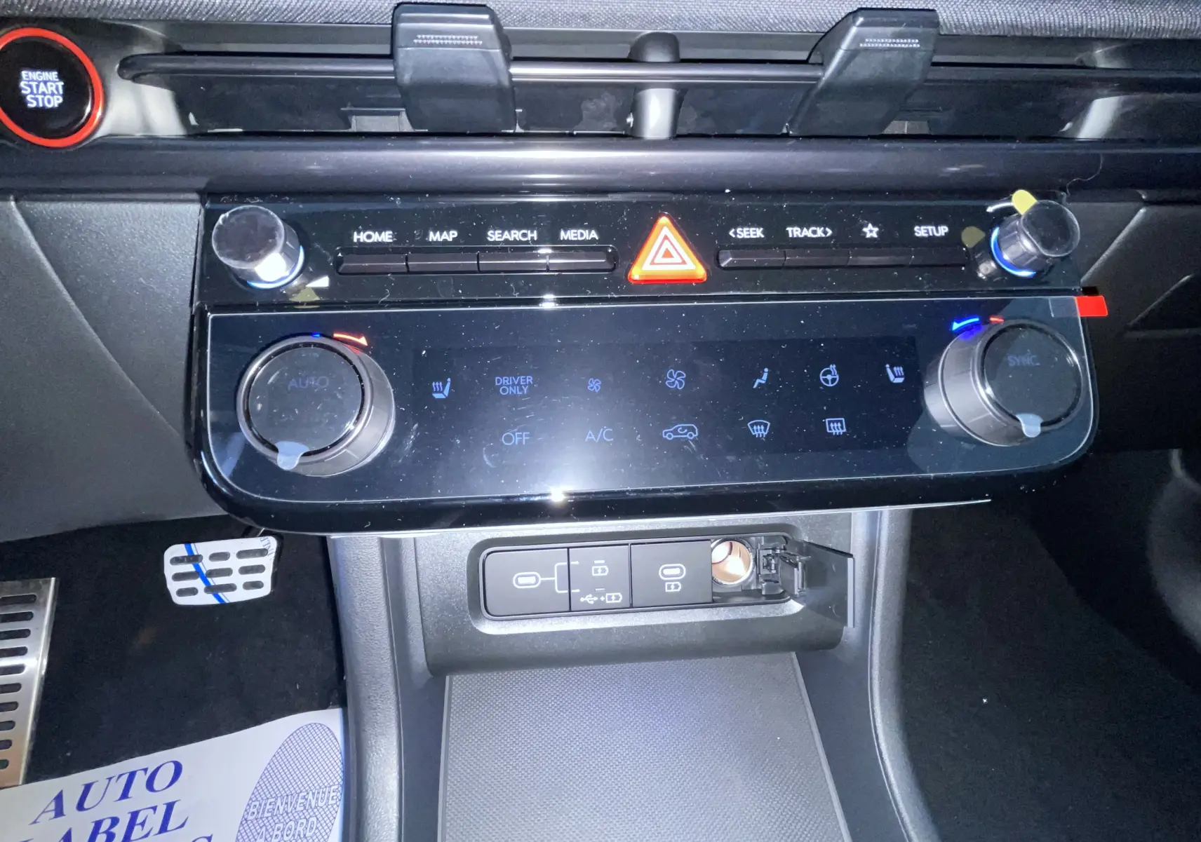 Vue rapprochée de la console centrale du Hyundai Tucson 2025, avec commandes tactiles et bouton start/stop rouge.