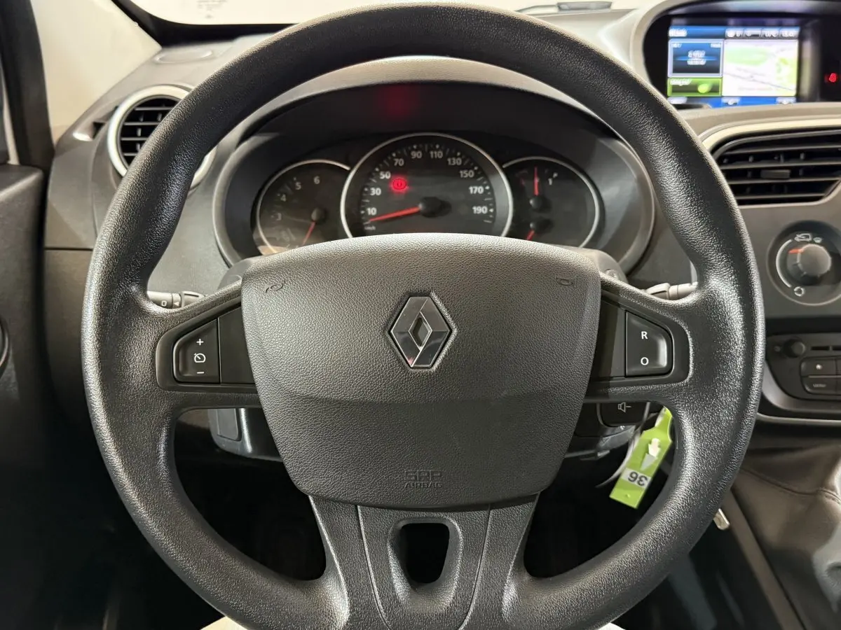 Vue rapprochée du volant noir Renault Kangoo 2021 avec commandes intégrées et tableau de bord numérique en arrière-plan.