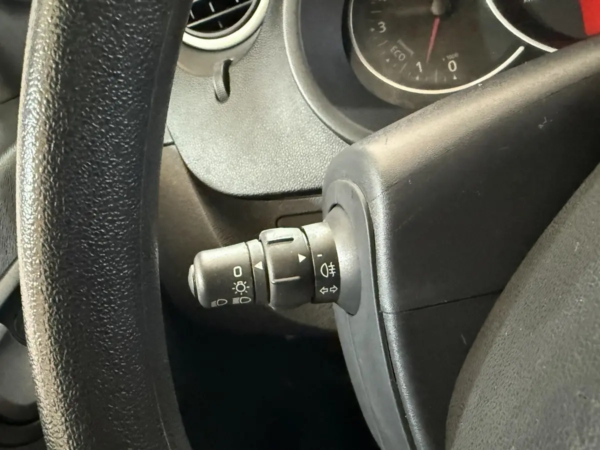 Gros plan sur la manette des phares à gauche du volant noir dans l’habitacle du Renault Kangoo blanc 2021.