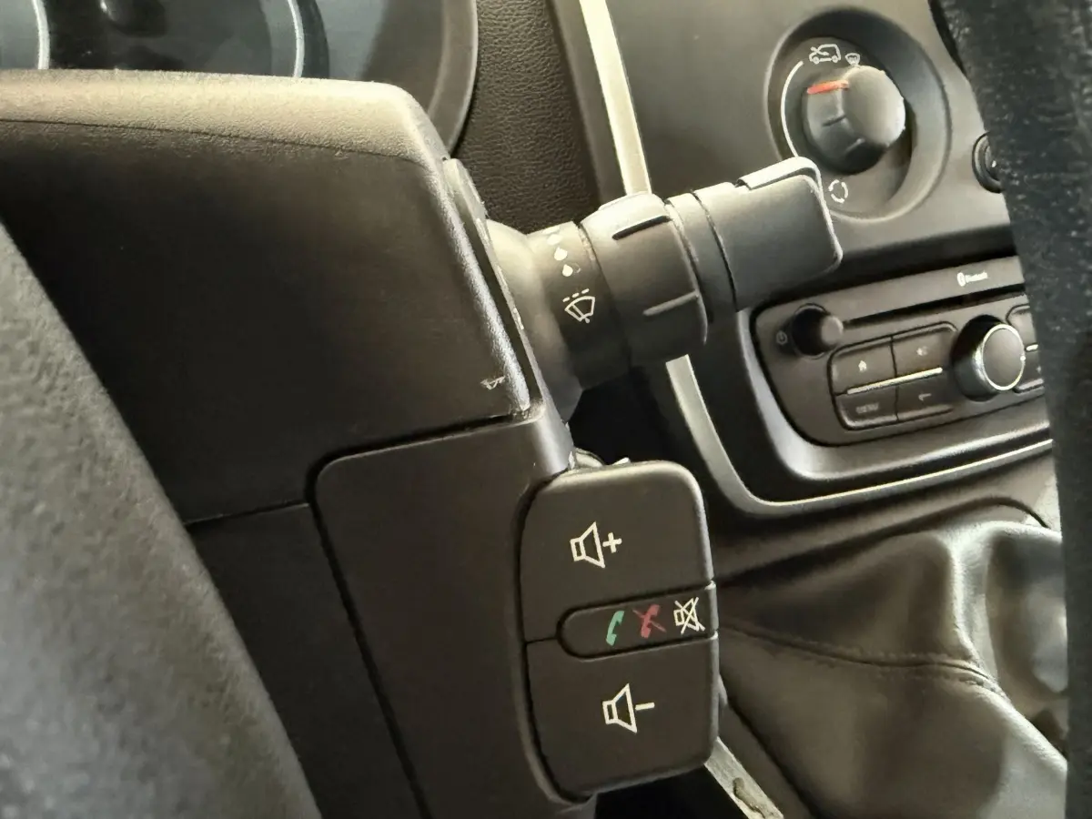 Gros plan sur les commandes au volant et la console centrale noire du Renault Kangoo Extra R-Link 2021, intérieur sombre.