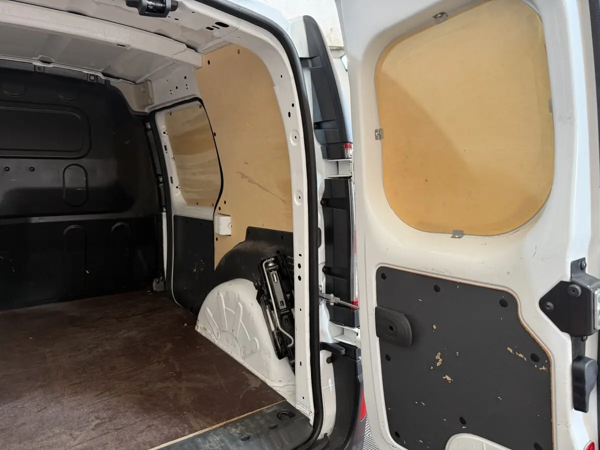 Vue intérieure arrière droite du Renault Kangoo Extra R-Link blanc, montrant l'espace de chargement avec cloison bois.