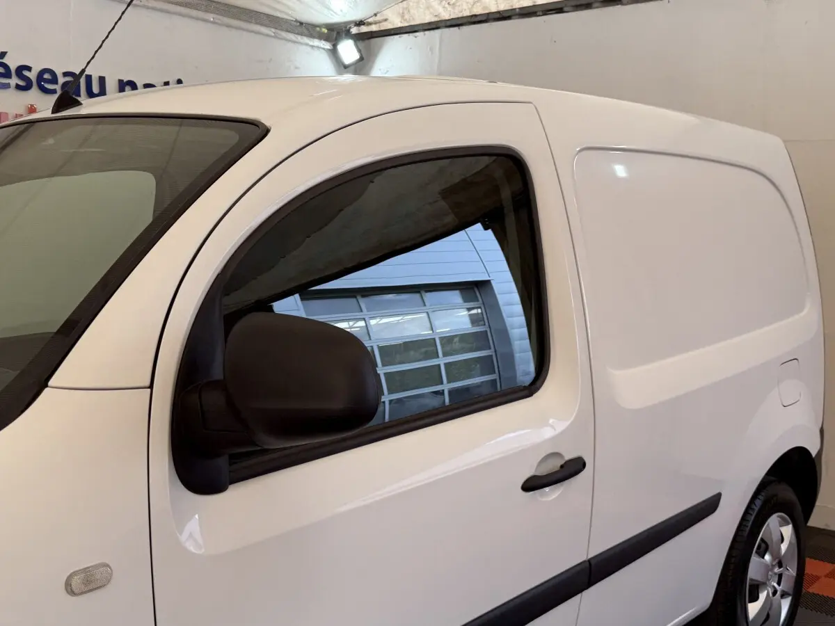 Vue de profil droit d’un utilitaire Renault Kangoo blanc avec porte latérale pleine et rétroviseur noir.