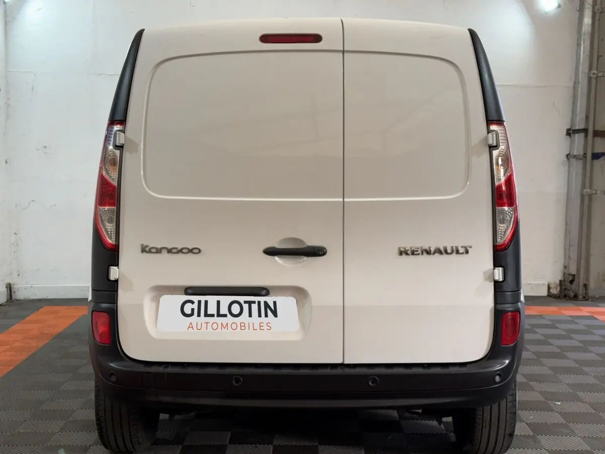 Vue arrière d’un Renault Kangoo blanc avec portes battantes et pare-chocs noir dans un garage.