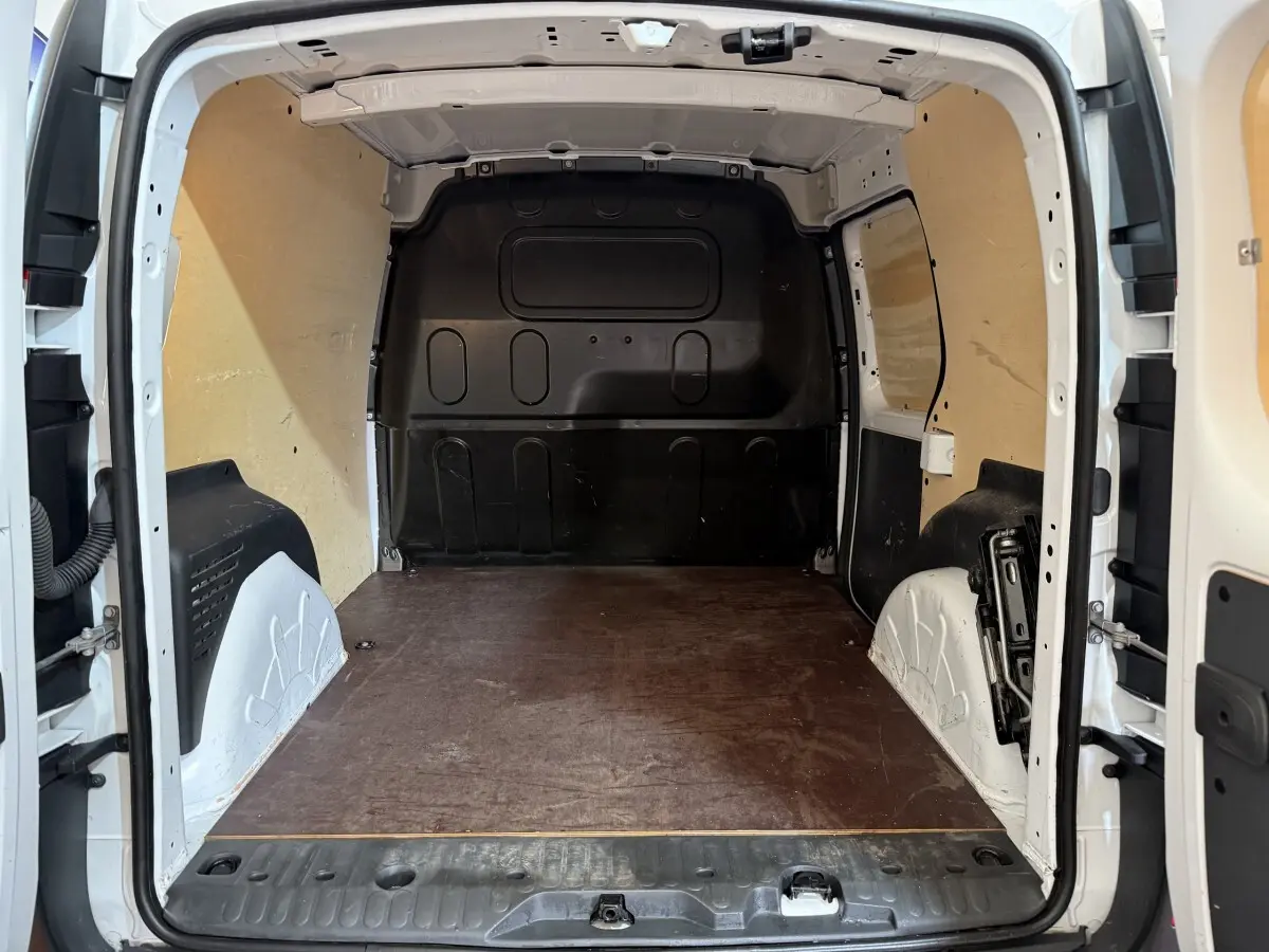Vue intérieure arrière du Renault Kangoo blanc 2021, montrant l'espace de chargement vide avec cloison pleine et plancher en bois.