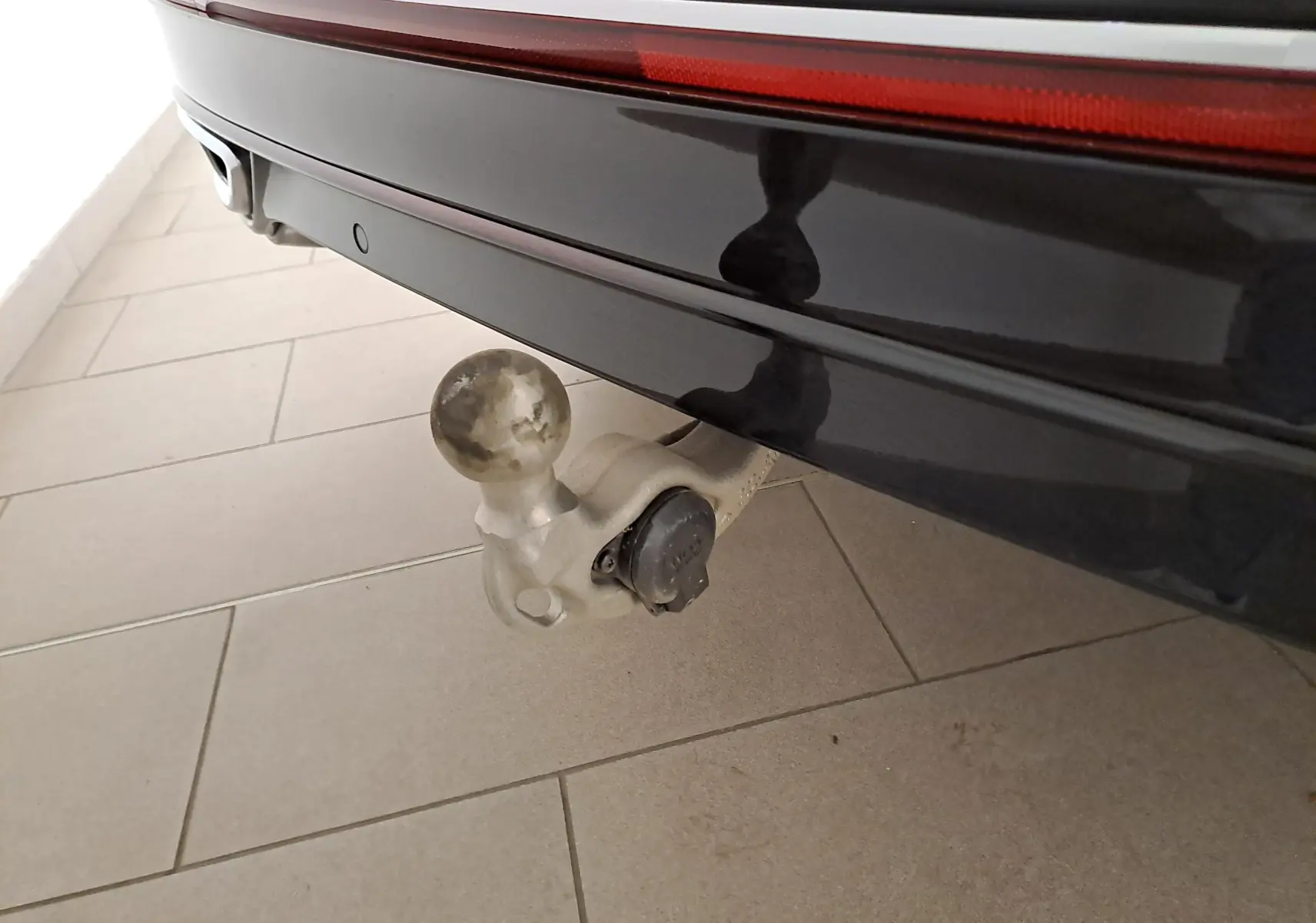 Gros plan sur le crochet d'attelage escamotable à l'arrière d'un Volkswagen Tiguan noir intense nacré.