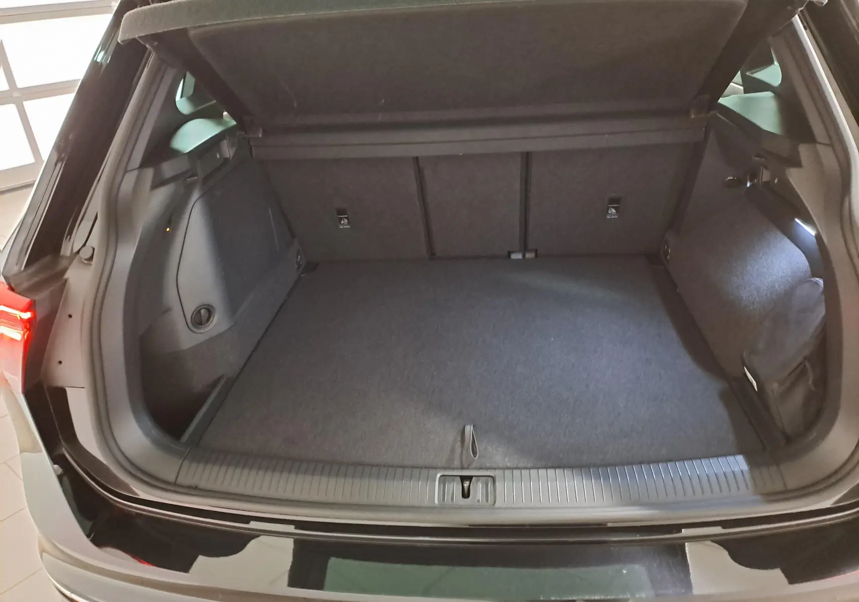 Coffre ouvert du Volkswagen Tiguan 1.4 eHybrid noir intense nacré, vue arrière montrant l’espace de chargement vide.