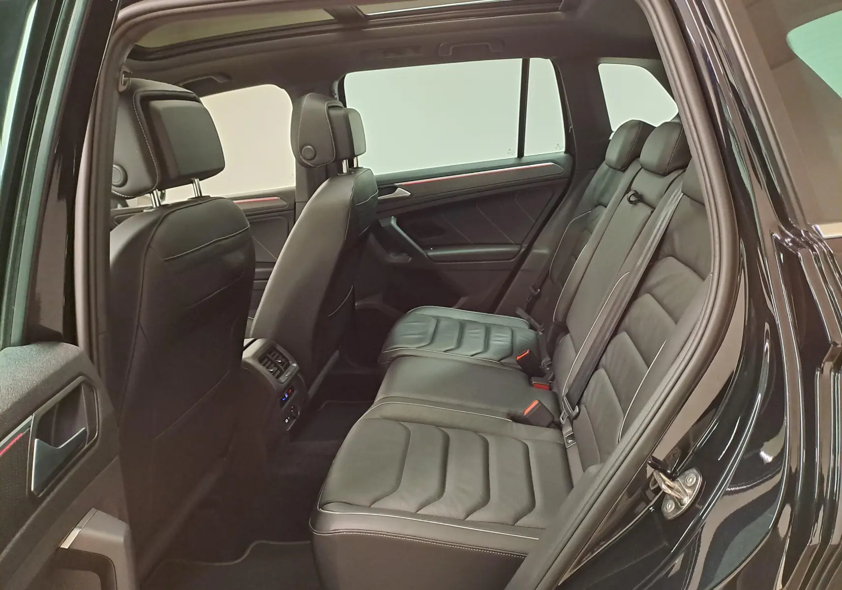 Vue intérieure côté droit du Volkswagen Tiguan 2023 noir intense nacré, montrant les sièges arrière en cuir et les finitions R-Line.