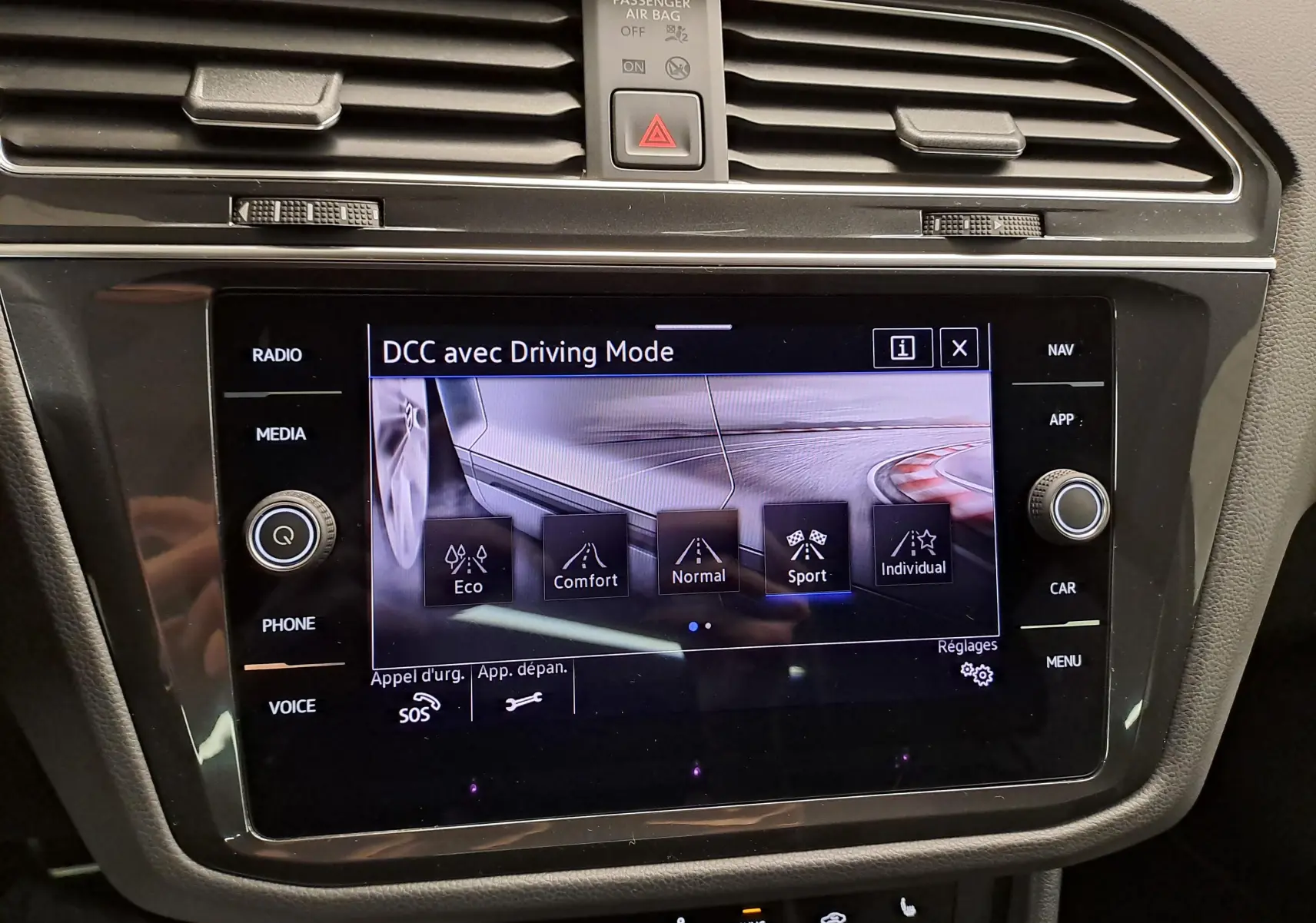 Écran tactile central du Volkswagen Tiguan 2023 affichant les modes de conduite DCC, entouré de commandes noires brillantes.