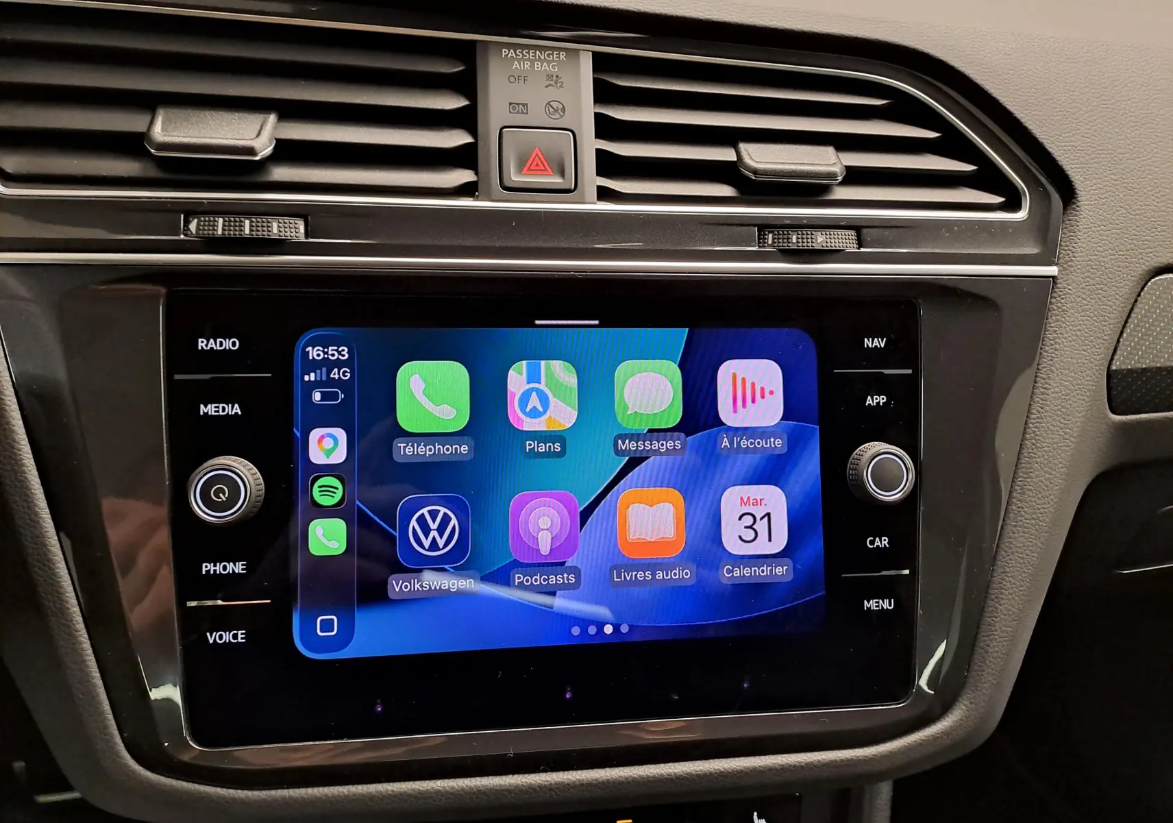 Vue rapprochée de l'écran tactile central du Volkswagen Tiguan 2023, affichant Apple CarPlay dans un intérieur noir.