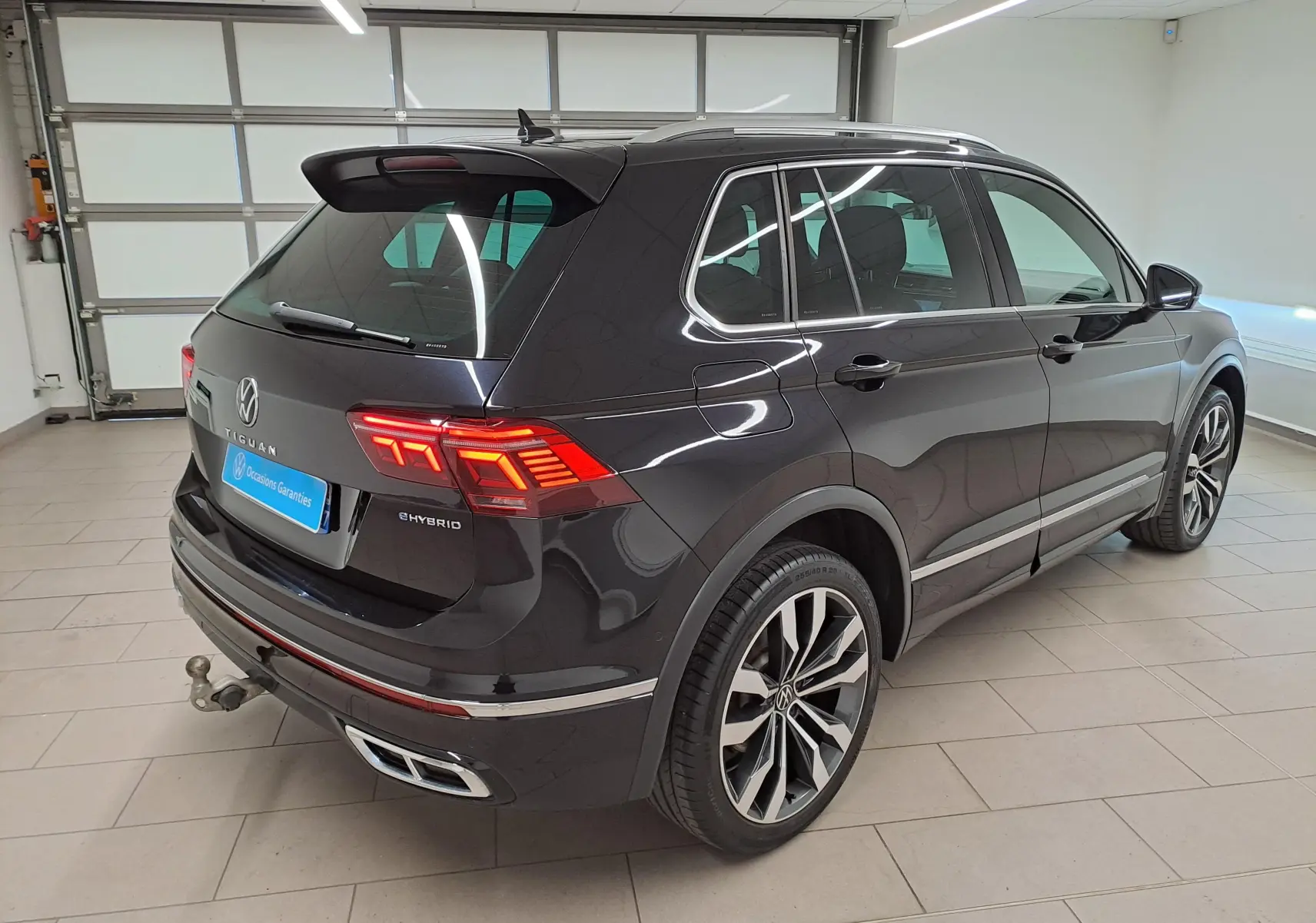 Vue 3/4 arrière droite du Volkswagen Tiguan 1.4 eHybrid noir intense nacré avec attelage escamotable et jantes 20 pouces Suzuka.