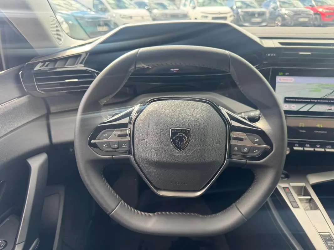 Vue centrée sur le volant noir du Peugeot 308 Hybrid 145 Allure 2025 avec tableau de bord numérique et écran tactile.