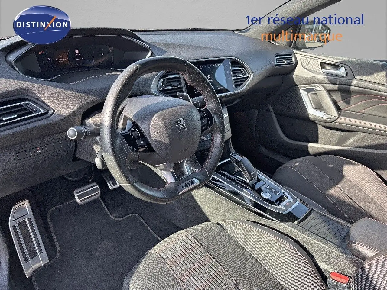 Intérieur de la Peugeot 308 GT 2021 vu côté conducteur, volant cuir perforé et console centrale moderne.