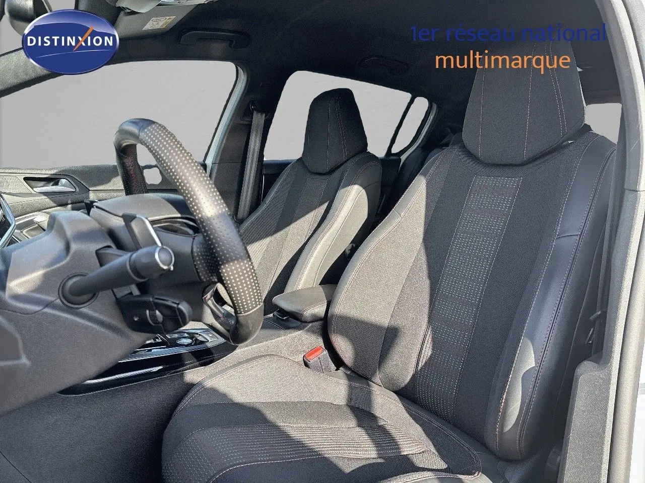 Intérieur de la Peugeot 308 GT 2021 vu côté conducteur, sièges en tissu noir avec surpiqûres rouges.